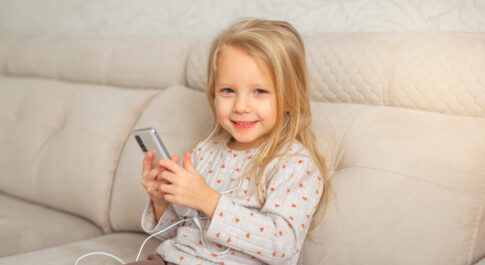 dziewczynka trzymająca telefon, która siedzi na kanapie