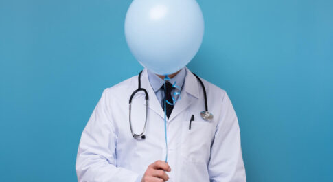 doktor, którego twarz zasłania niebieski balonik.