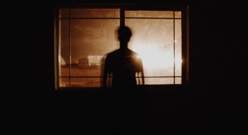 Kontur człowieka stojącego w oknie. Zdjęcie zrobione w sepii.