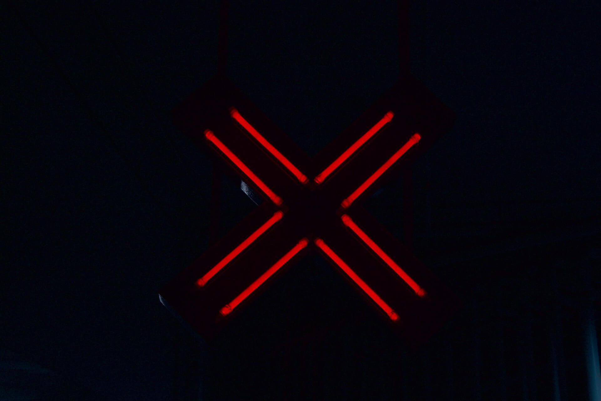 Duży, czerwony, neonowy "x", na czarnym tle. 
