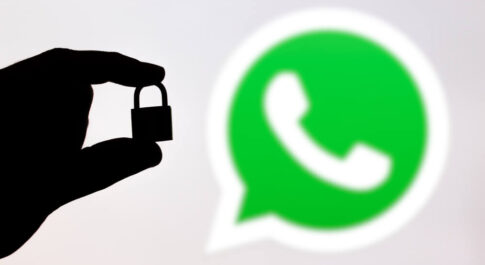 na szarym tle, po prawej stronie znajduje się logo WhatsAppa, a po lewej cień ręki trzymającej kłódkę.