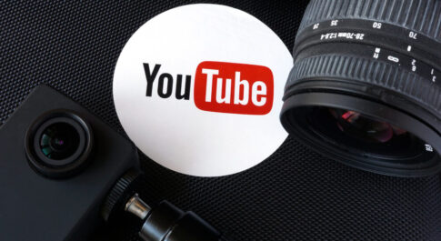 Logo serwisu YouTube, w otoczeniu aparatów, na czarnym tle.