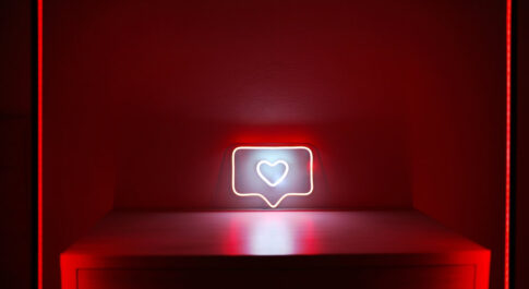 Neon w kształcie serca z Instagrama, na czerwonym podeście i czerwonym tle.