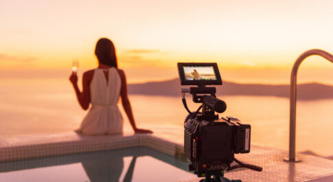Kobieta siedząca tyłem, patrząca na morze. Za nią ustawiony aparat, którym zrobi sobie zdjęcie.