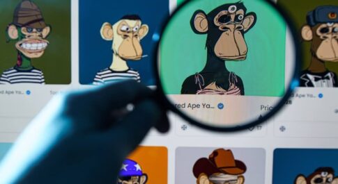 Na monitorze kilka obrazów NFT. Jeden, z małpą, jest pod lupą, którą trzyma ręka w kolorach retro.