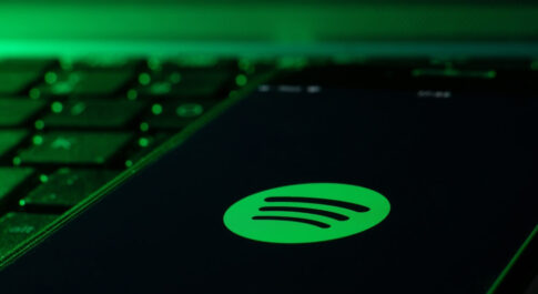 Telefon z włączonym Spotify, leżący na czarnej klawiaturze. Na to wszystko zielone światło.
