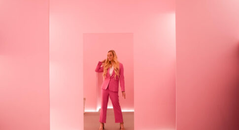 Kobieta ubrana w różowy garnitur, na tle różowych ścian. Influencer marketing.