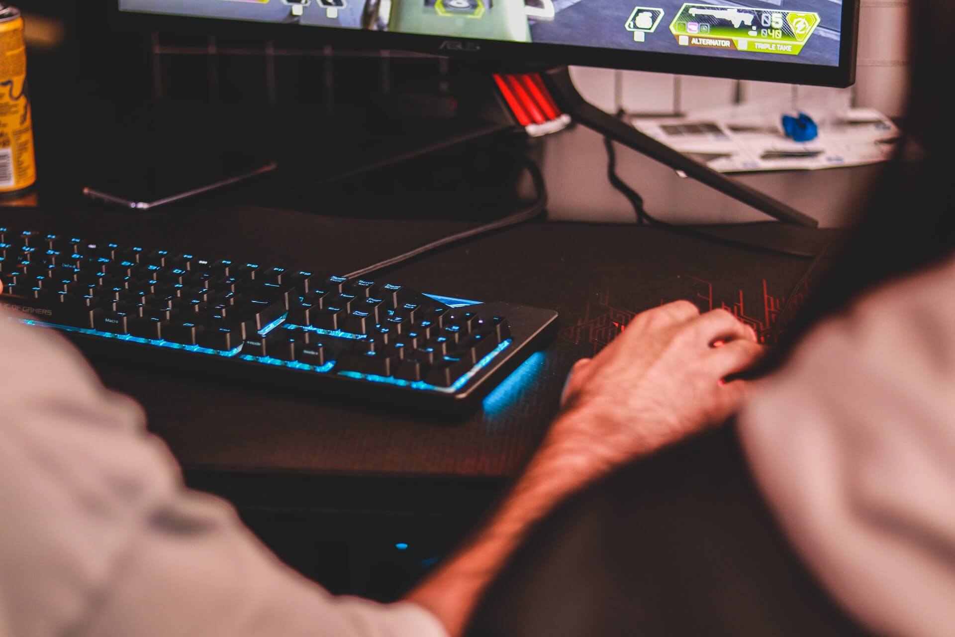 Widok na klawiaturę graczy i rękę trzymającą myszkę od komputera. 