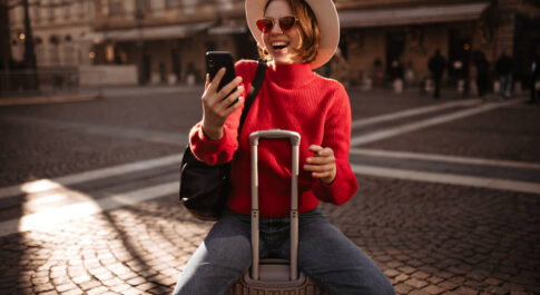 Dziewczyna siedząca na walizce z telefonem w ręku.
