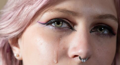 Kobieta z różowymi włosami, z której oka płynie łza.