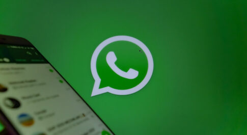 logo whatsapp, obok włączony telefon z aplikacją.