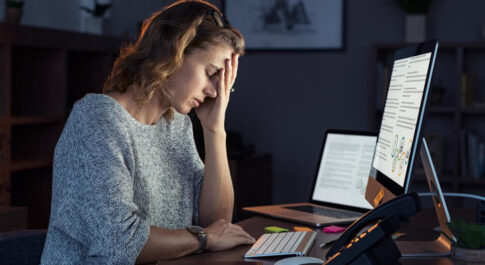 Zmęczona kobieta siedząca przed ekranem laptopa.