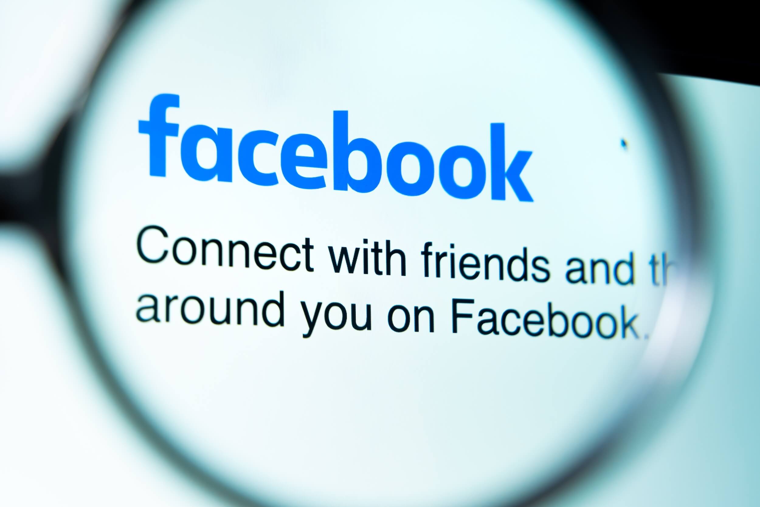 ekran z logo Facebooka pod lupą