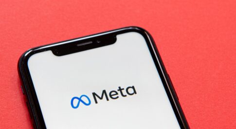 Logo Meta na ekranie smartfona leżącego na czerwonym tle