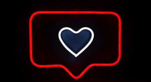 Neon z sercem oznaczającym polubienie na Instagramie, na czarnym tle.