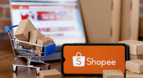 Logo Shoppe na smartfonie, laptop z widokiem platformy w tle
