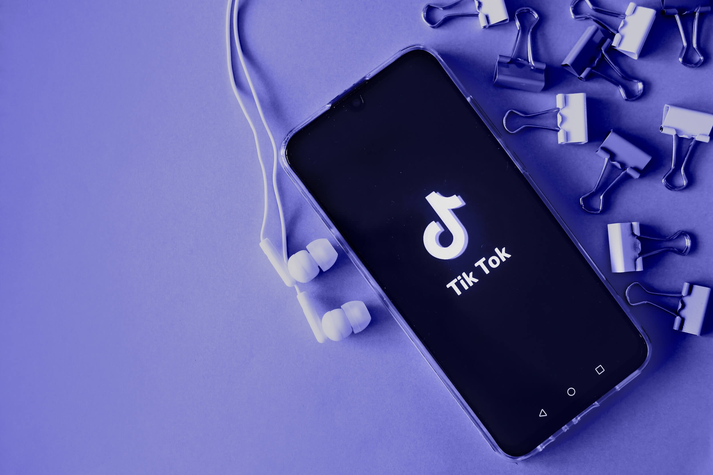 Smartfon z aplikacją TikToka na fioletowym tle