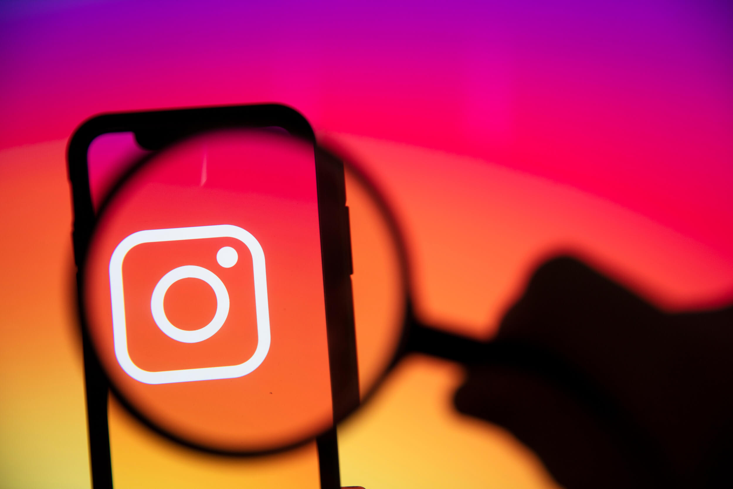 Logo Instagrama pod lupą; reklama na Instagramie